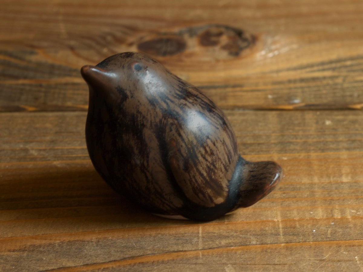濃い茶色の鳥のオブジェの拡大。黒に近い筋が縦に流れる釉薬。